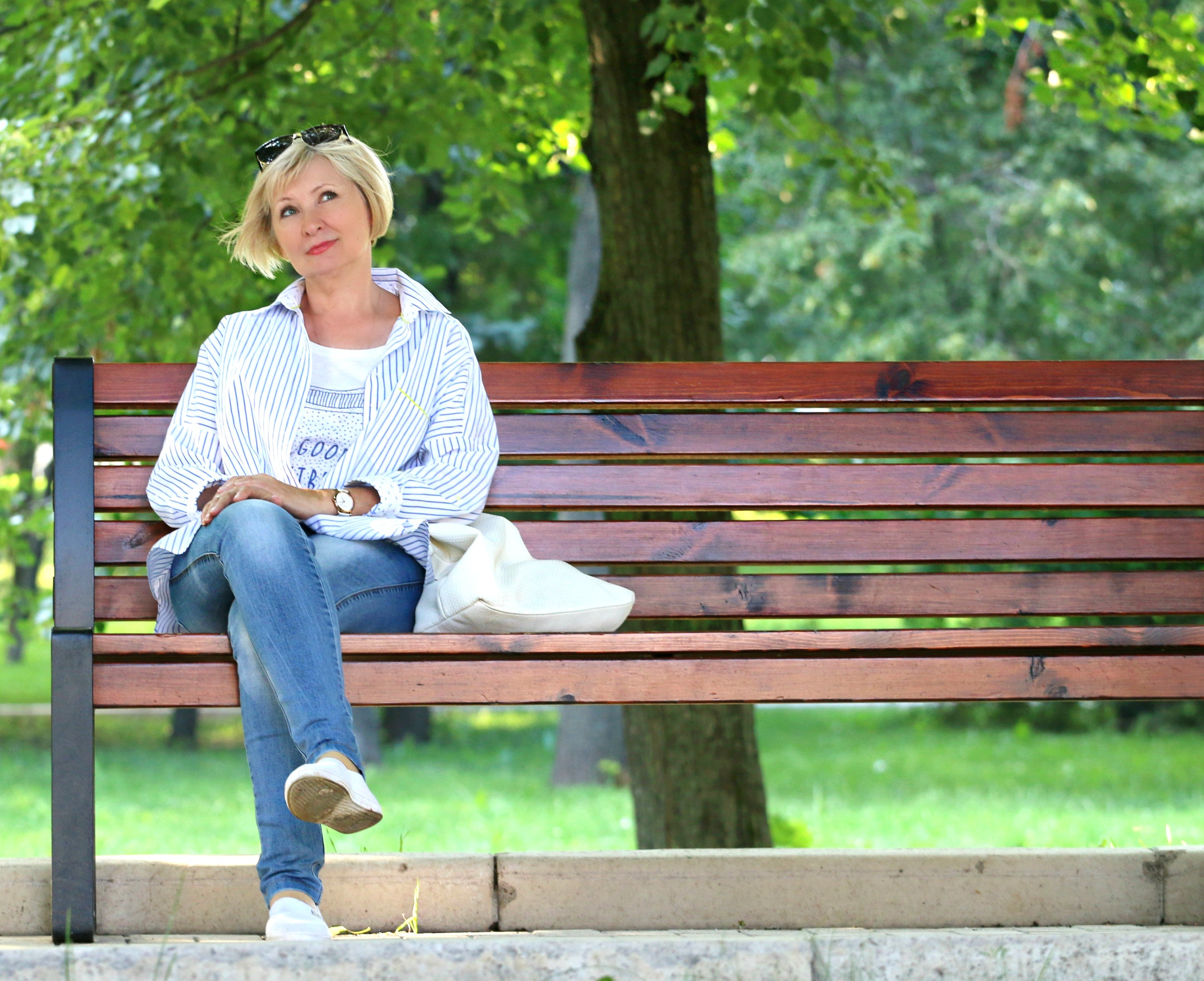 A photo showing a lady going through the menopause sitting in a park