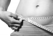 An image showing a fit woman measuring her waist