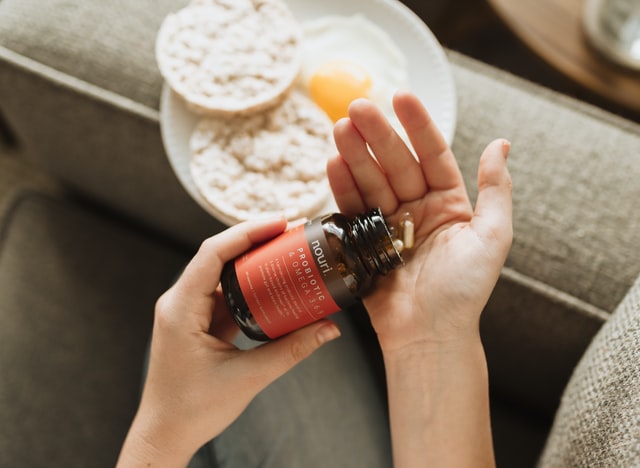 a women holding a probiotic supplement in hand