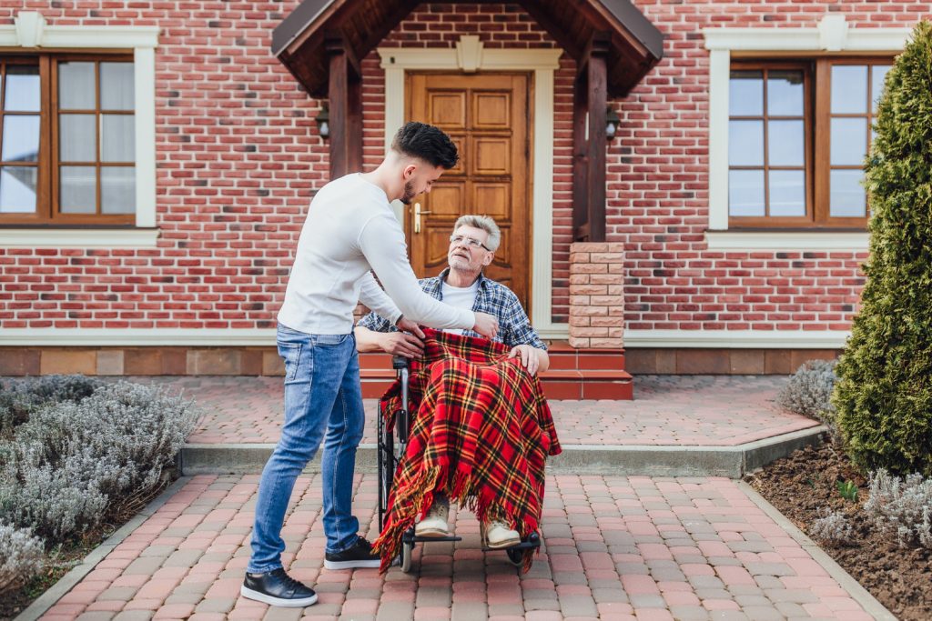 7 Effective Strategies for Managing Chronic Illness With Aging 4 son helping his father wheelchair near nursing home